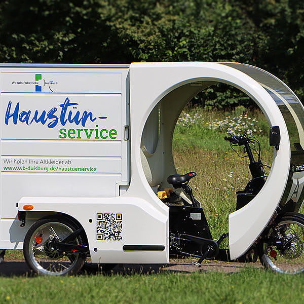 Kleines E-Lastenfahrrad mit angehängtem Anhänger des WBD-Haustürservices.